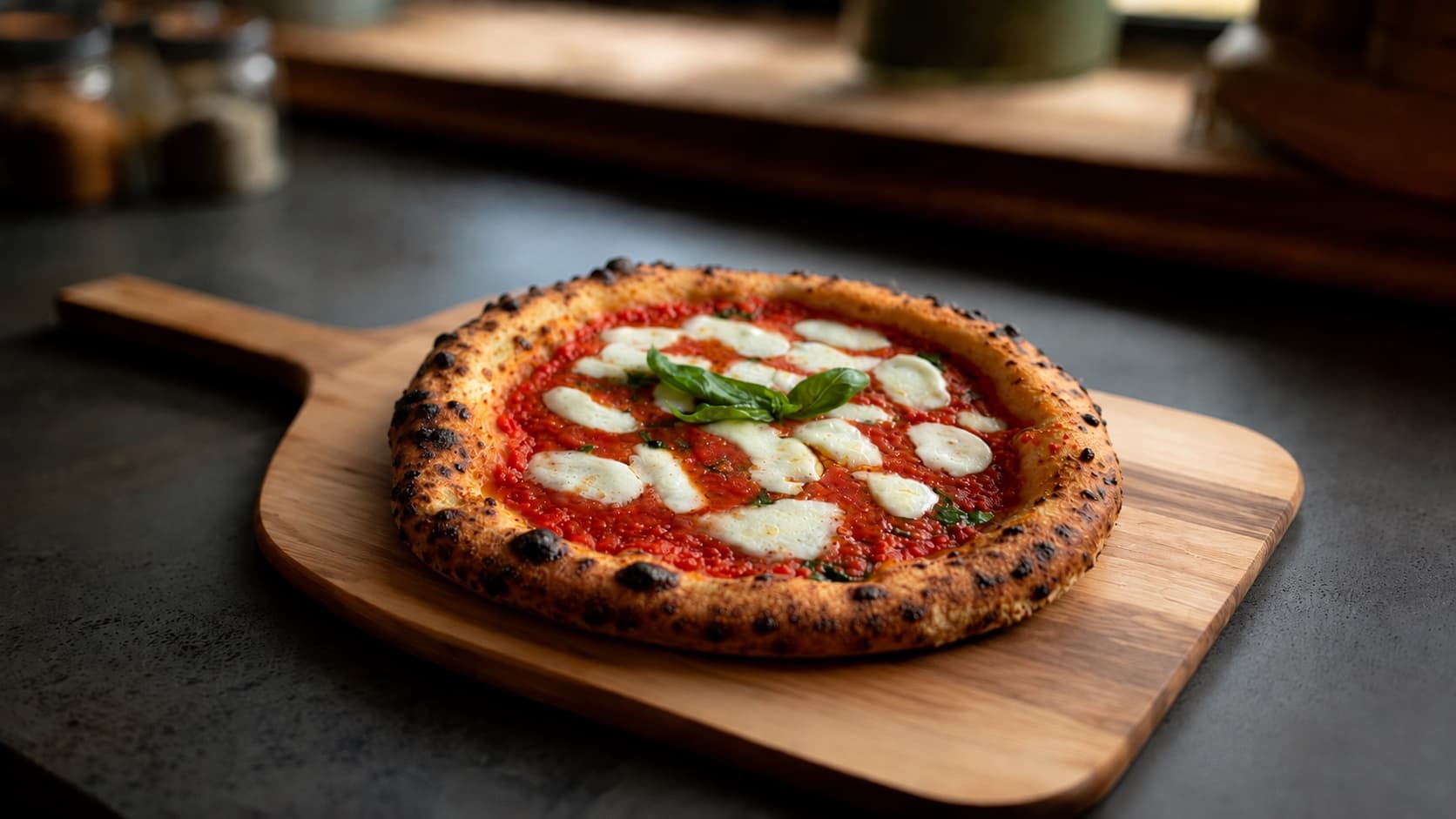A handmade Neapolitan pizza on a wooden peel